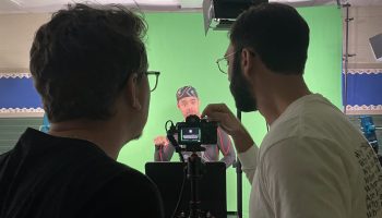 Justin Perez, Deafverse narrator, warms up for a scene while Chase, media coordinator, and Ruan, video editor, sets up the camera.