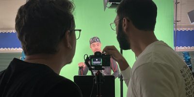 Justin Perez, Deafverse narrator, warms up for a scene while Chase, media coordinator, and Ruan, video editor, sets up the camera.