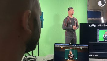 Kent, game designer, is watching Justin rehearse in front of a green screen.