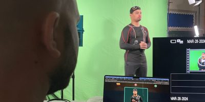 Kent, game designer, is watching Justin rehearse in front of a green screen.
